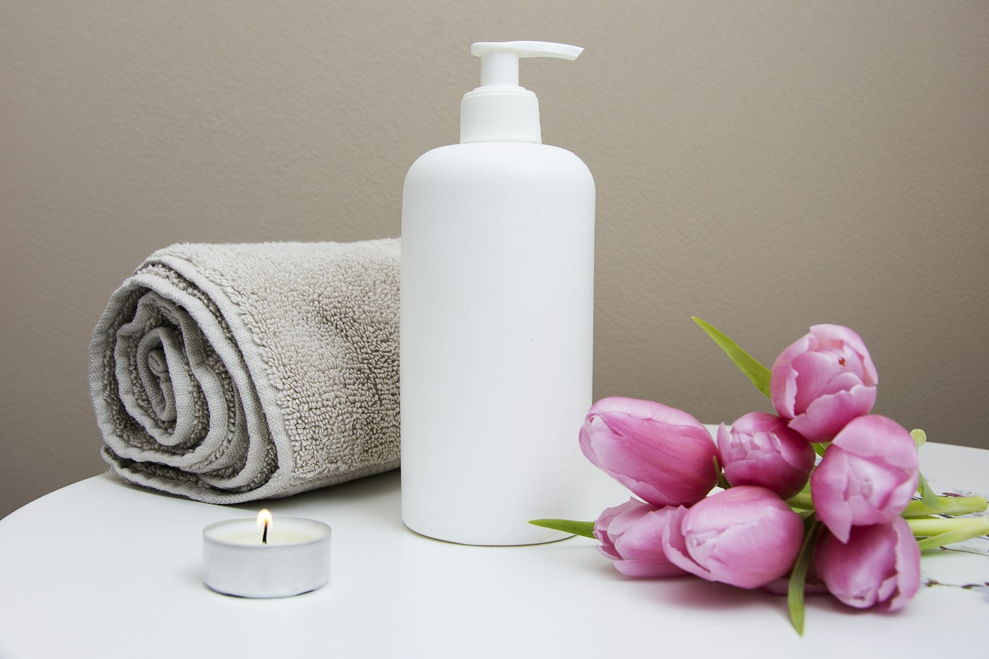 Spa still life with folded towels, massage oil, candles and orchids